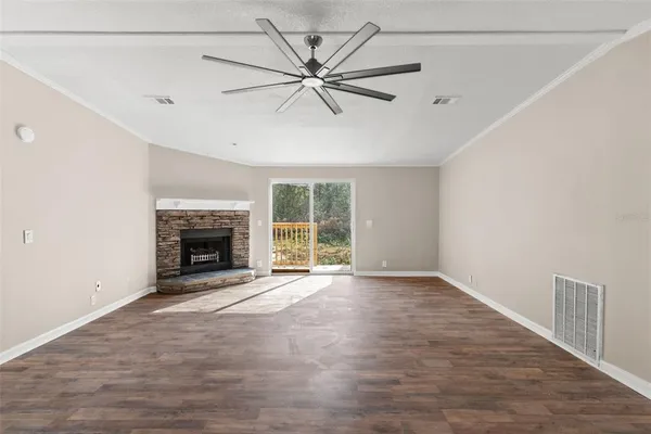 an empty room with chandelier fan and windows