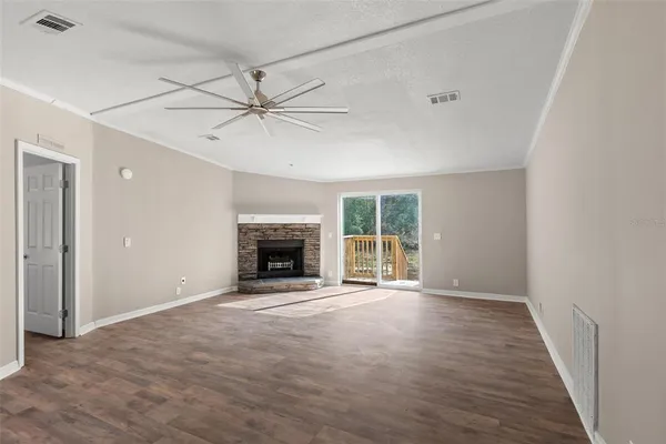 an empty room with windows fireplace and a ceiling fan