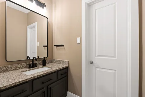 a bathroom with a granite countertop sink and a mirror