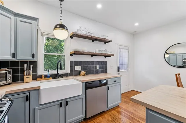 a kitchen with a sink dishwasher a stove a microwave oven a dining table and chairs with wooden floor