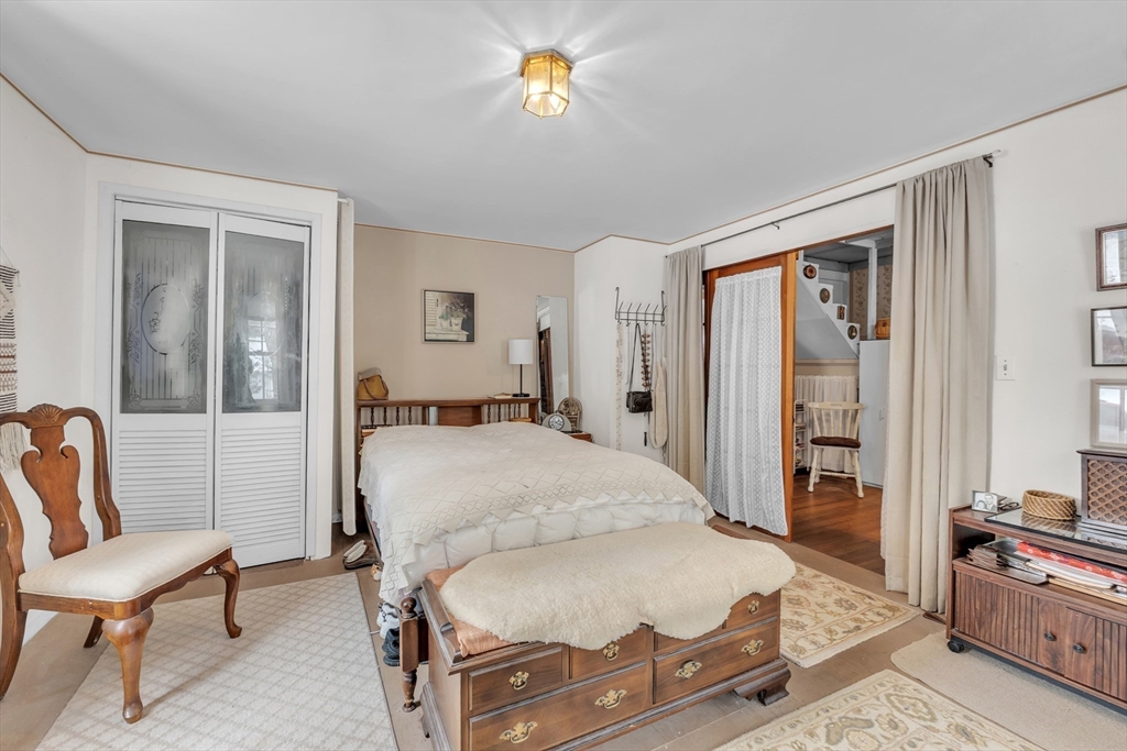 228 Walnut Hill Road Orange, MA 01364 - Photo 8 of 20 a bedroom with a bed a chandelier and mirror