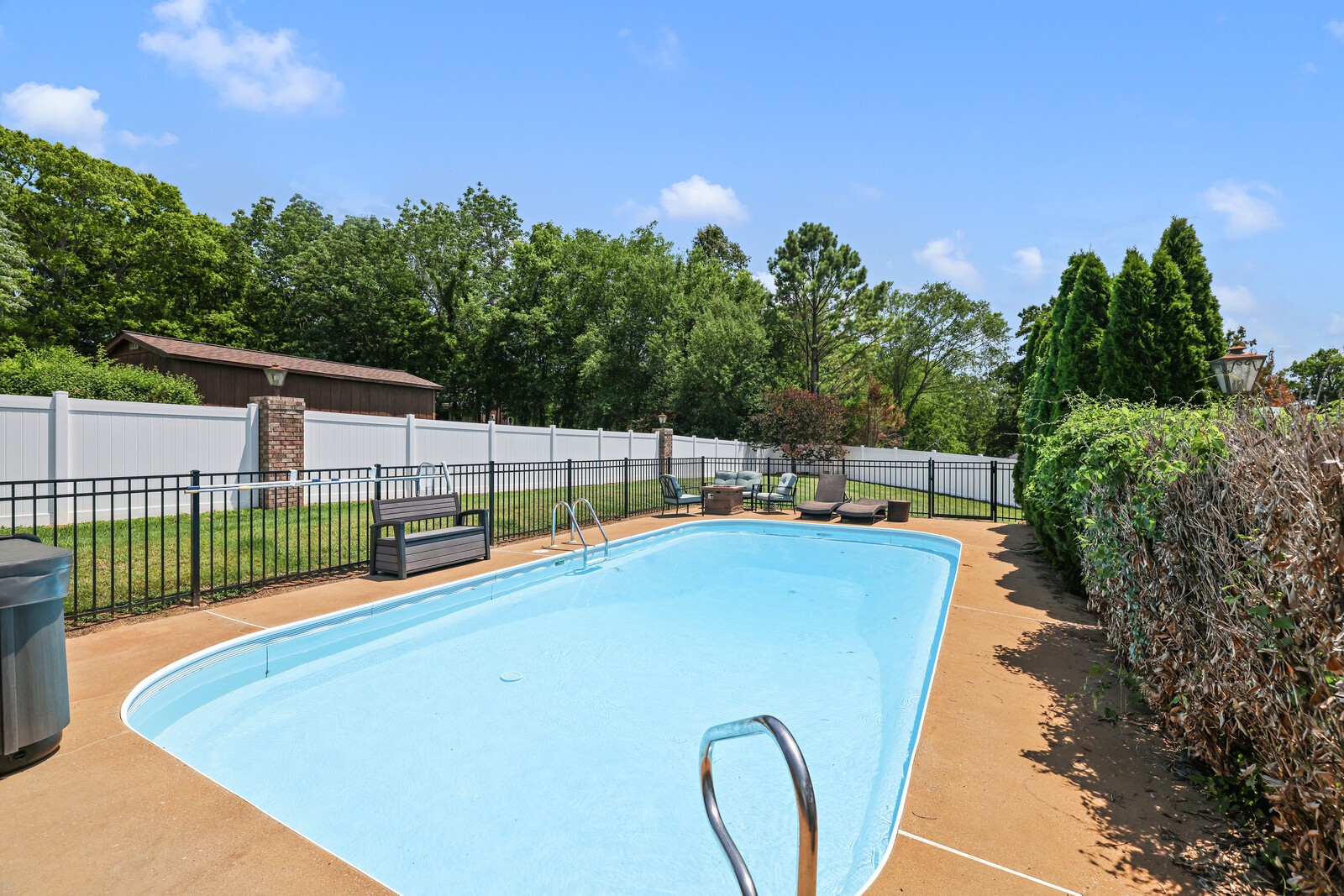 a view of a backyard with swimming pool and trees in the background