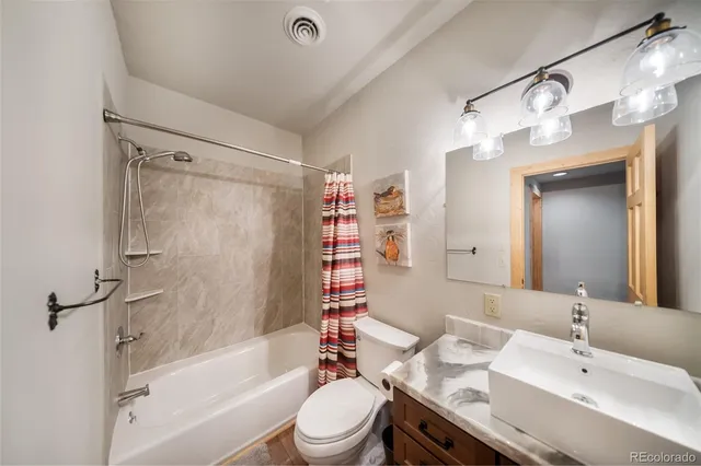 a bathroom with a bathtub shower sink vanity mirror and toilet