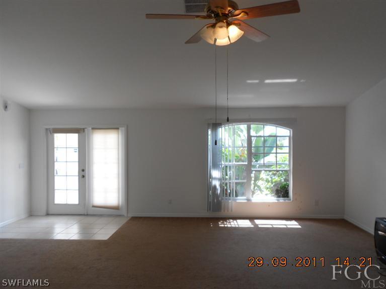 217 Rue Labonne Road Fort Myers, FL 33913 - Photo 3 of 8 an empty room with windows and chandelier fan