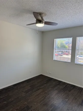 an empty room with wooden floor ceiling fan and window