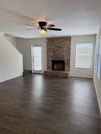 an empty room with wooden floor fireplace and windows