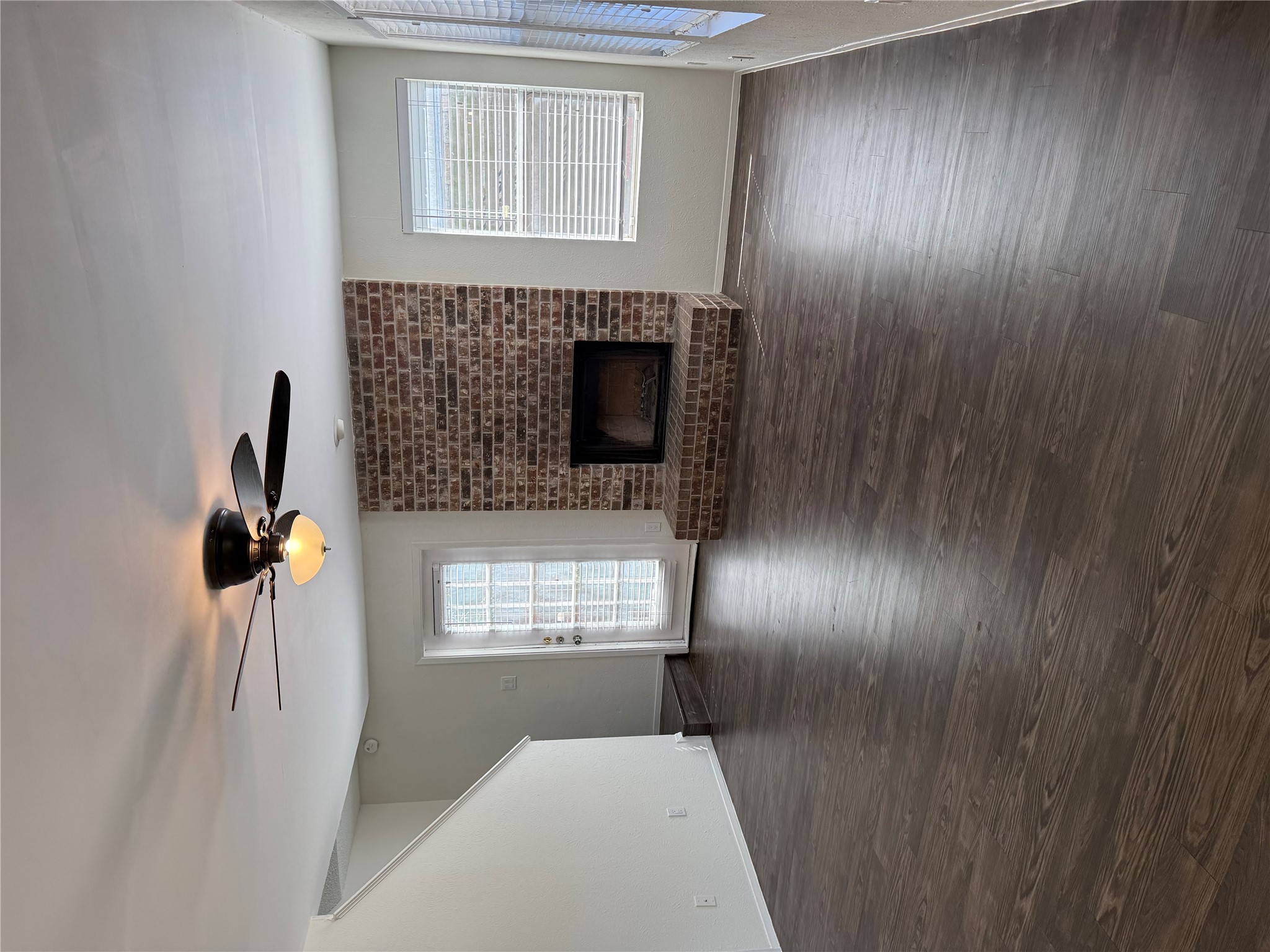 11807 Alpheus Avenue, Unit B Austin, TX 78759 - Photo 6 of 16 Unfurnished living room featuring ceiling fan, a brick fireplace, and dark wood-style floors