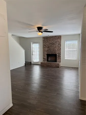 an empty room with wooden floor fireplace and windows