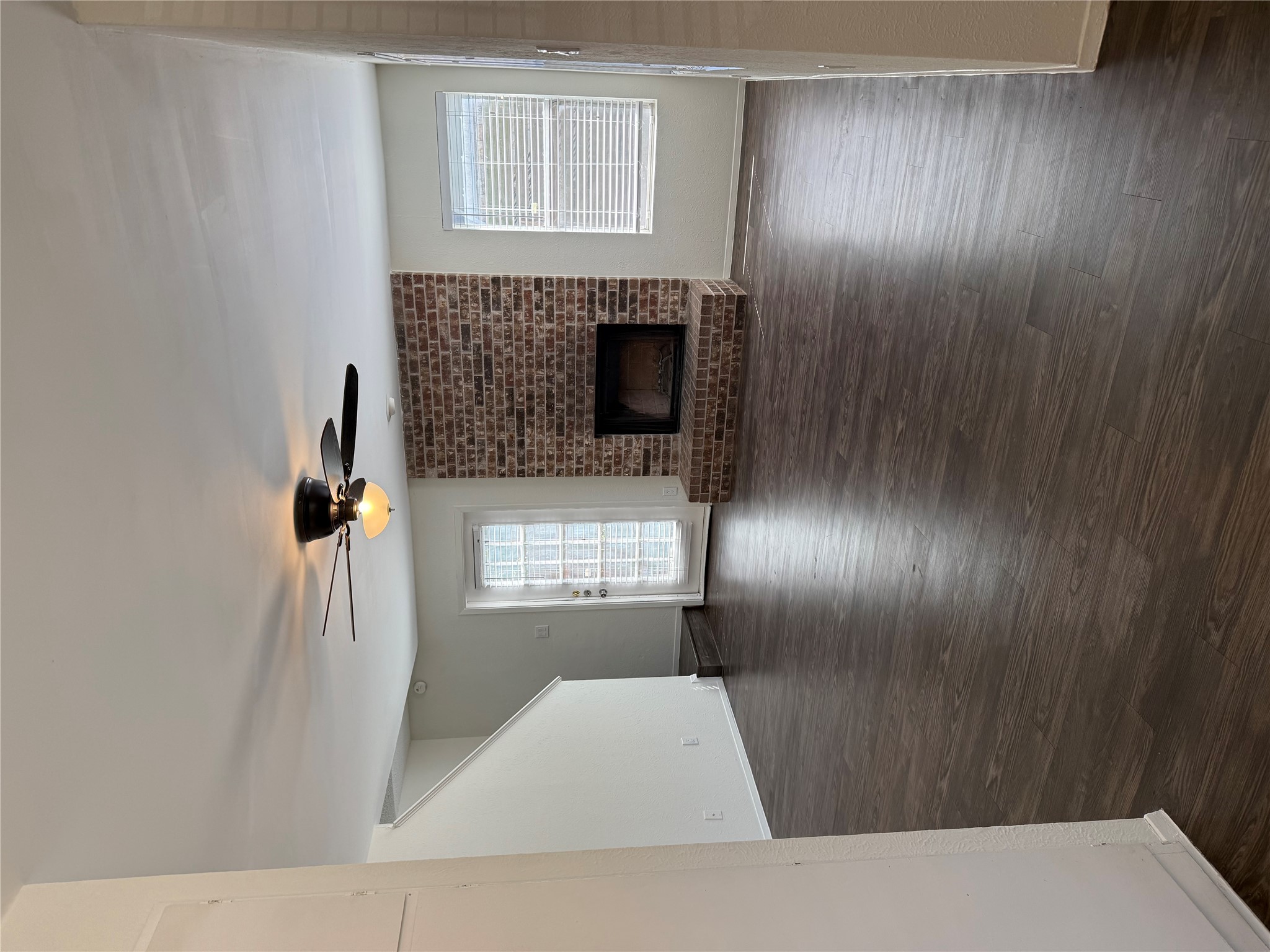 11807 Alpheus Avenue, Unit B Austin, TX 78759 - Photo 7 of 16 Unfurnished living room featuring a ceiling fan, a fireplace, and dark wood-style flooring