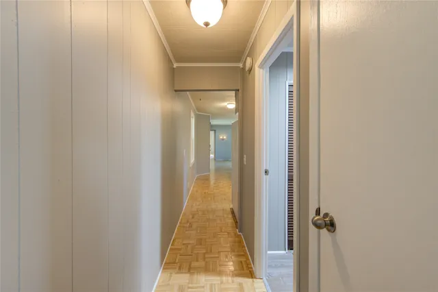 a view of a hallway with wooden floor and a bathroom