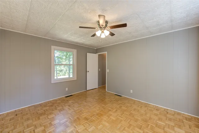 an empty room with windows and fan