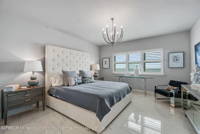 a bedroom with a bed and a chandelier next to a window