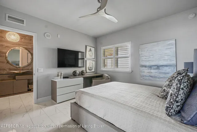 a bedroom with a bed flat screen tv and windows