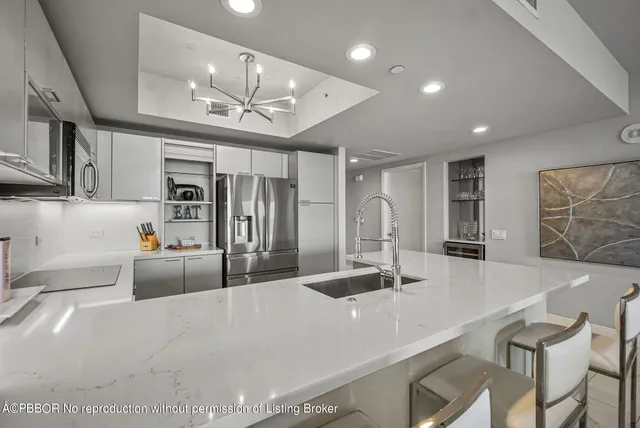 a large kitchen with stainless steel appliances a large counter top a stove and a chandelier