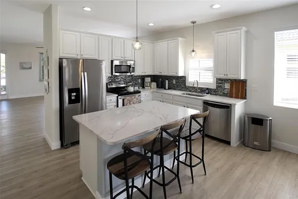 a kitchen with stainless steel appliances a stove a sink a refrigerator white cabinets and a refrigerator