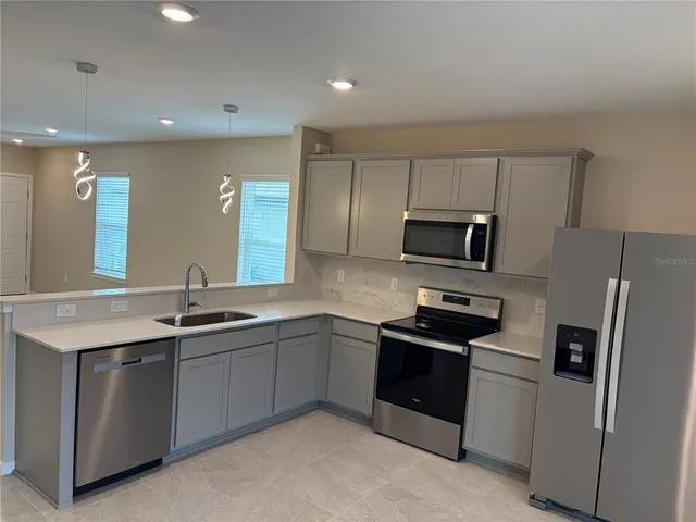 a kitchen with stainless steel appliances granite countertop a refrigerator and a sink