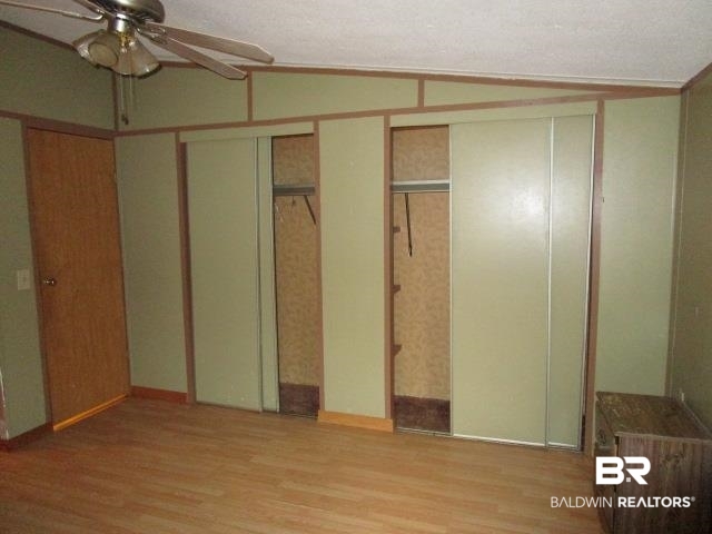 20705 Greek Cemetery Road Robertsdale, AL 36567 - Photo 12 of 25 Unfurnished bedroom featuring light wood finished floors, a ceiling fan, and multiple closets