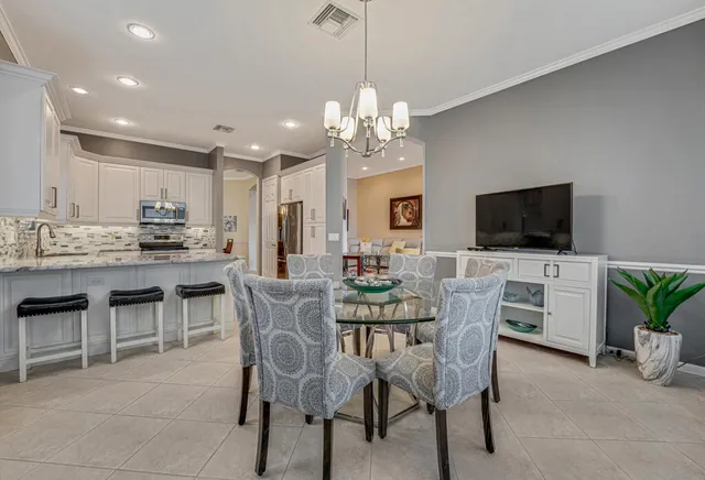 a view of a dining room with furniture a kitchen and chandelier