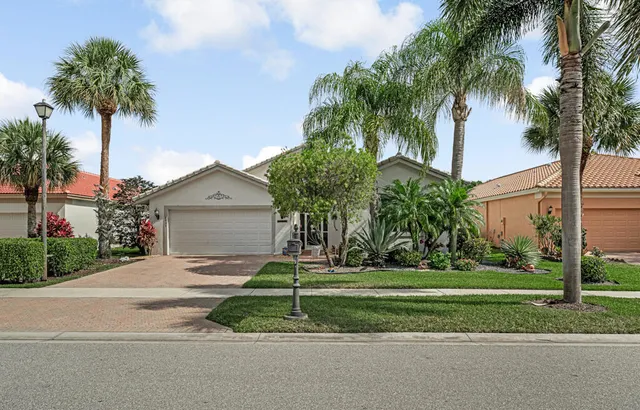 a view of a house with a yard and palm trees