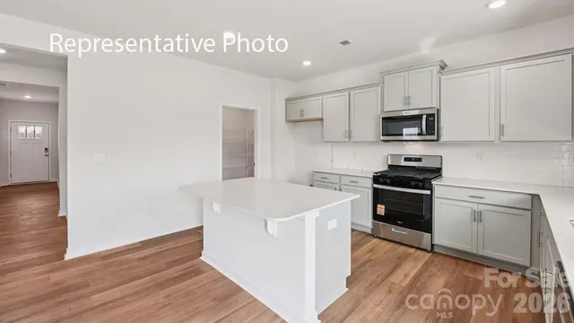 a kitchen with stainless steel appliances a white stove top oven cabinets and a wooden floor