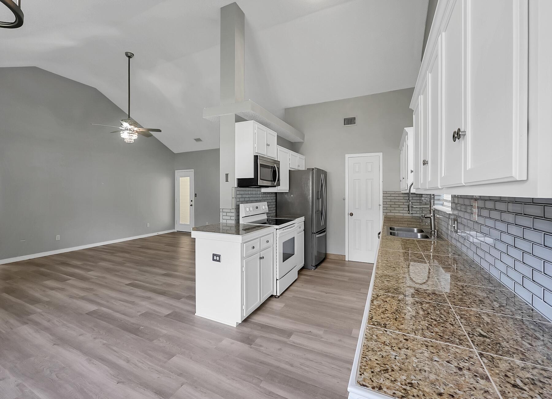 129 Wright Circle Niceville, FL 32578 - Photo 11 of 44 a large white kitchen with wooden floor and stainless steel appliances