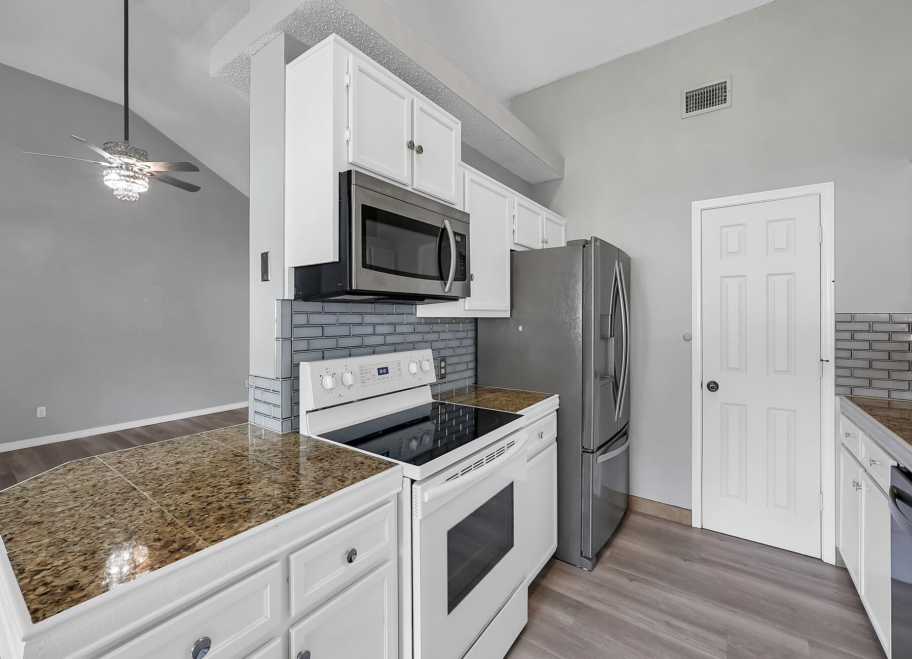 129 Wright Circle Niceville, FL 32578 - Photo 12 of 44 a kitchen with stainless steel appliances granite countertop a refrigerator a stove a sink and white cabinets with wooden floor