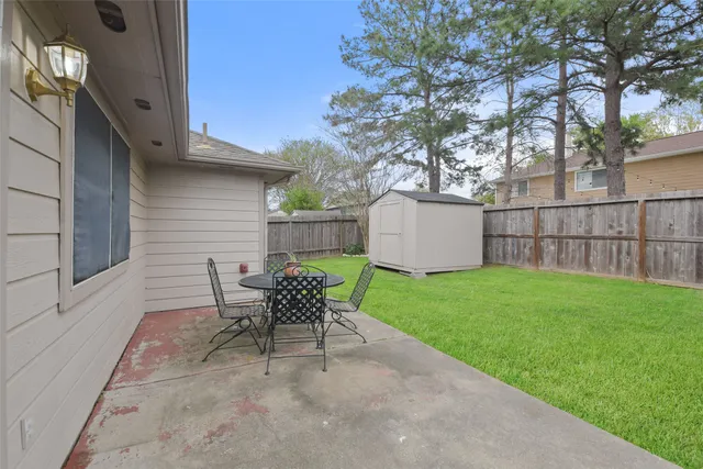 a patio with a table and chairs and potted plants