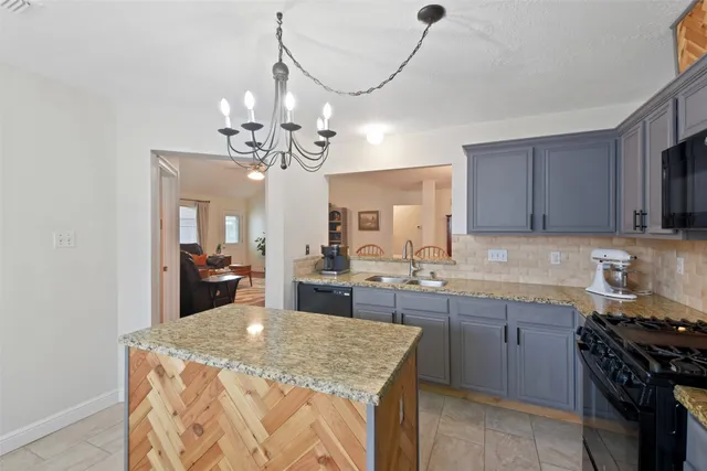a kitchen with stainless steel appliances granite countertop a sink a stove top oven a counter space and cabinets