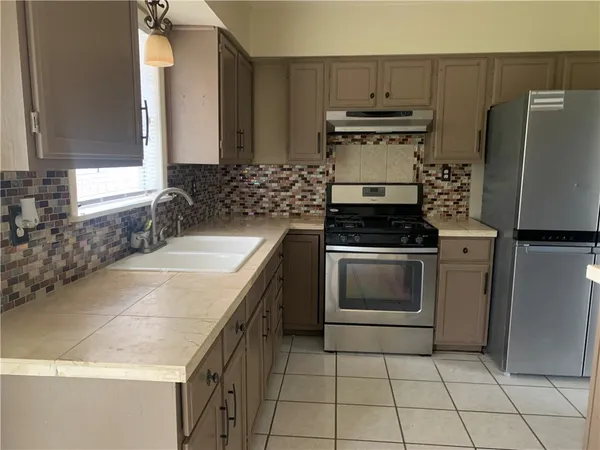 a kitchen with granite countertop a sink stove and refrigerator