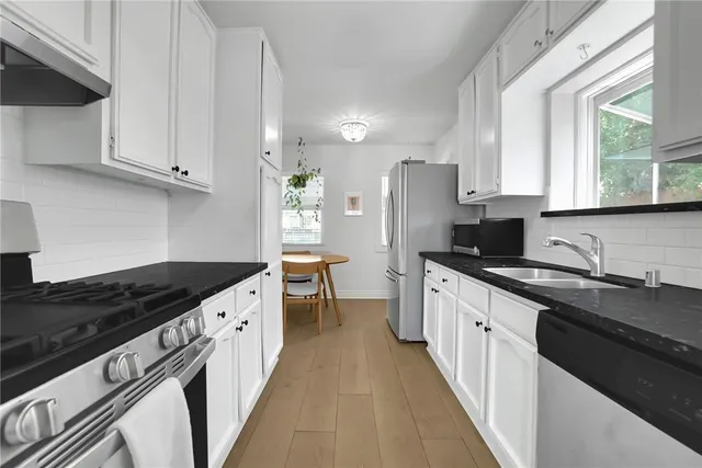 a kitchen with granite countertop a sink stove refrigerator and cabinets