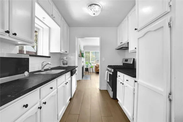 a kitchen with granite countertop a sink stove and cabinets
