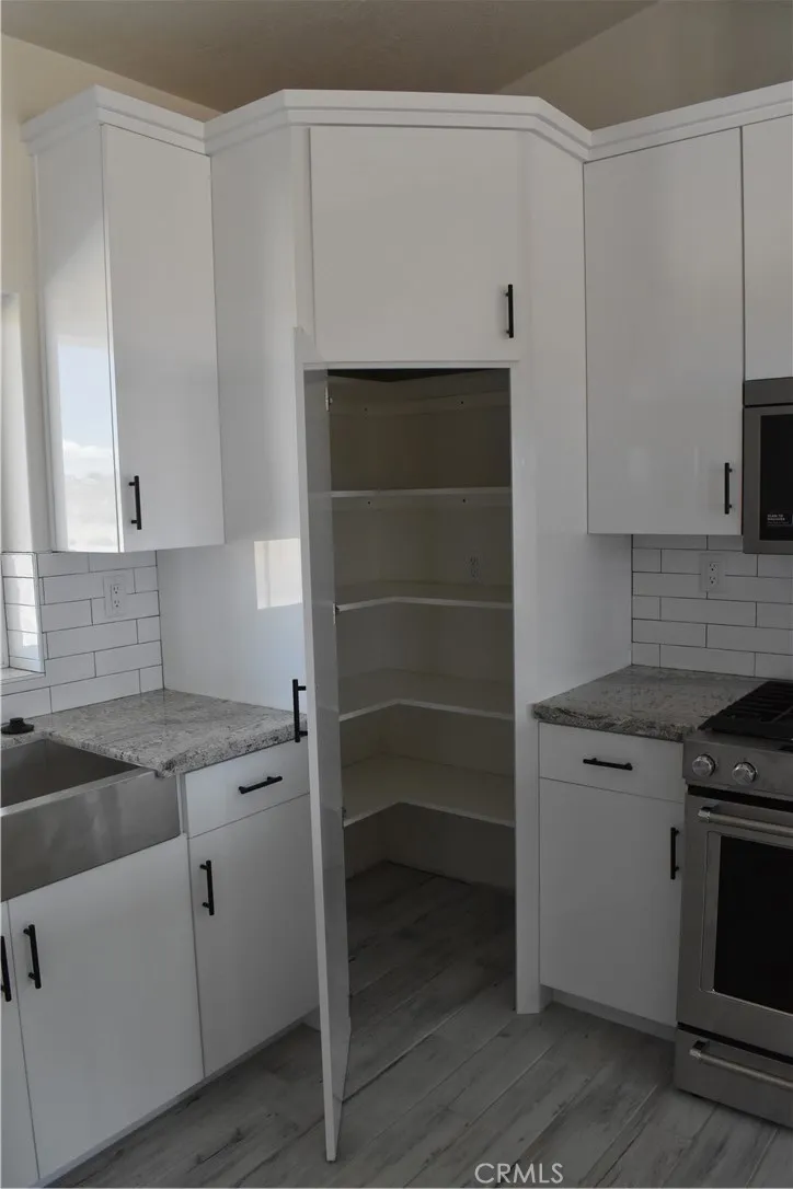 16944 Pauhaska Road Apple Valley, CA 92308 - Photo 25 of 74 a kitchen with white cabinets and a stove