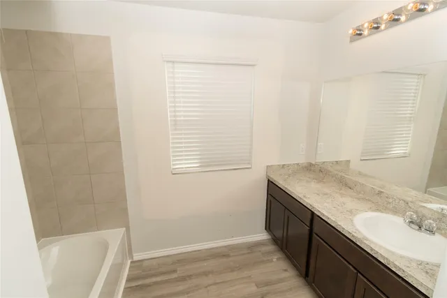 a bathroom with a granite countertop sink a mirror and a bathtub