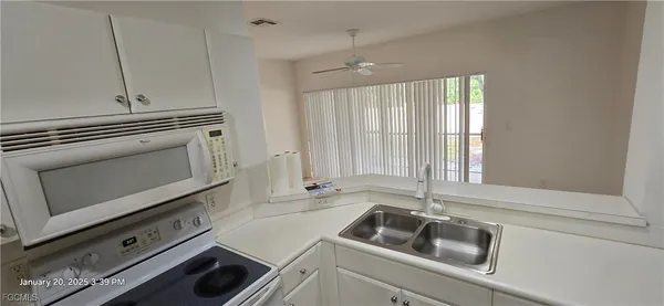 a kitchen with granite countertop white cabinets sink and stainless steel appliances