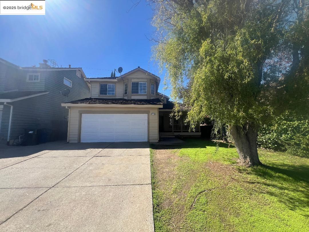 View of front of home featuring a front lawn, concrete driveway, and an attached garage