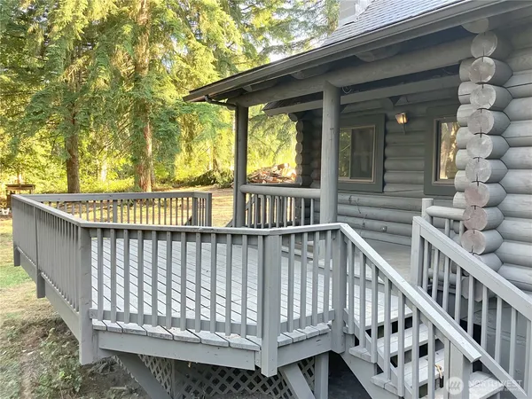 a view of deck with large trees and wooden fence