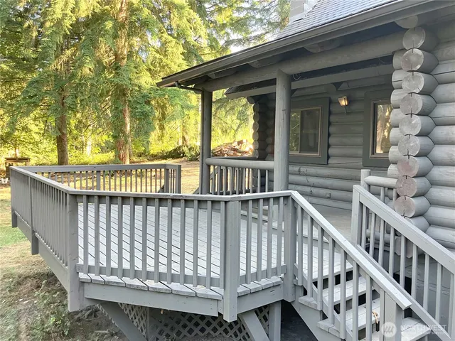 a view of deck with large trees and wooden fence