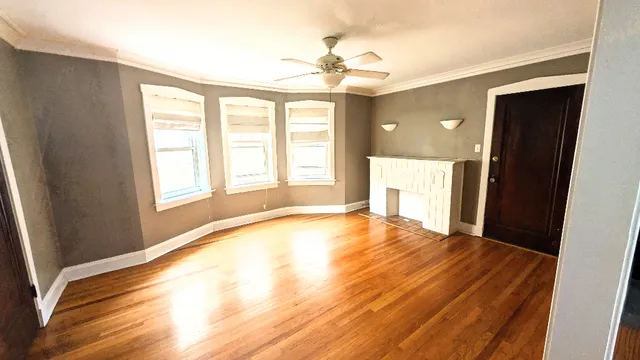 a view of an empty room with a window and wooden floor