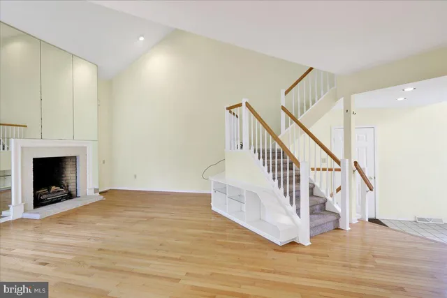 a view of an empty room with wooden floor a fireplace and a window