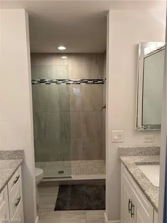 a bathroom with a granite countertop sink a mirror and shower