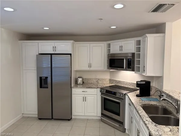 a kitchen with stainless steel appliances granite countertop a refrigerator and a sink