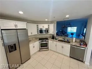 a kitchen with granite countertop stainless steel appliances a sink a counter top space and cabinets