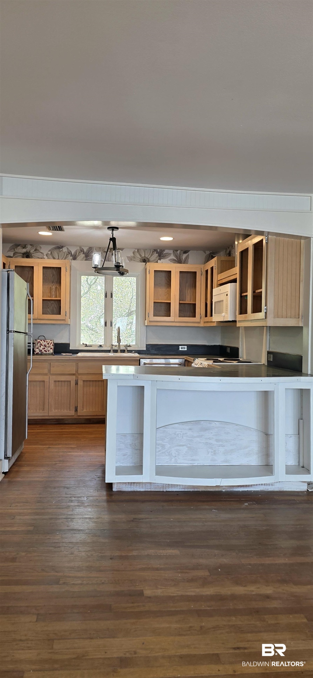 544 Windmill Ridge Road Gulf Shores, AL 36542 - Photo 22 of 50 Kitchen featuring white microwave, freestanding refrigerator, dark wood-type flooring, glass insert cabinets, and dark countertops