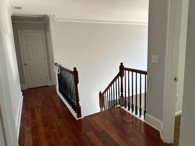a view of a hallway with wooden floor and a bathroom