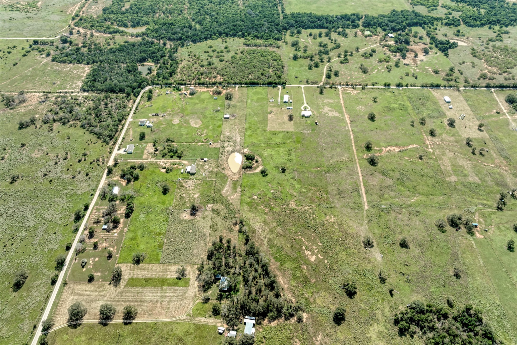 5309 Tenney Creek Road Luling, TX 78648 - Photo 20 of 23 An aerial perspective reveals vast acreage with interspersed trees, scattered structures, and a tranquil pond.