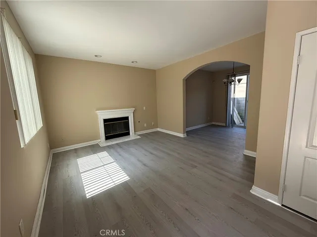 an empty room with wooden floor fireplace and windows