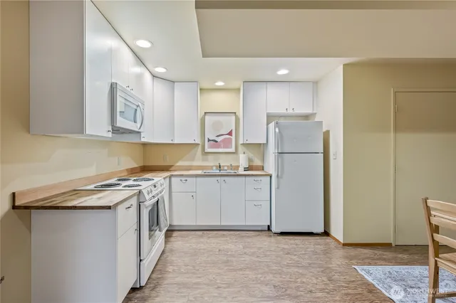 a kitchen with a refrigerator a stove top oven and white cabinets