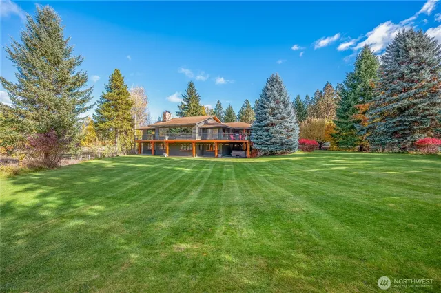 a view of a house with a big yard and large trees
