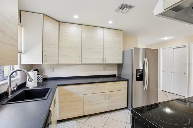 a kitchen with stainless steel appliances granite countertop a sink a refrigerator and cabinets