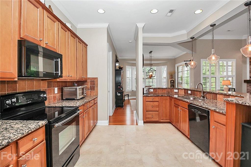2018 Dynasty Court Fort Mill, SC 29708 - Photo 7 of 31 a large kitchen with stainless steel appliances granite countertop a stove top oven a sink dishwasher a dining table and chairs with wooden floor